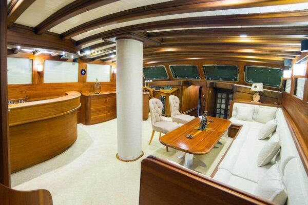 wicked-felina-gulet-photo19 Elegant interior of a Gulet yacht showcasing luxurious wooden furnishings, a cozy seating area, and panoramic windows, perfect for upscale Gulet charter experiences in Turkey.