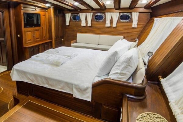 wicked-felina-gulet-photo23 Luxurious wooden interior bedroom on a Gulet yacht, featuring a cozy bed, elegant curtains, and classic maritime design, perfect for comfortable Turkish gulet charter experiences.